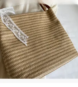 Vue détaillée du sac cabas en paille tressée avec ruban en dentelle blanche et anses