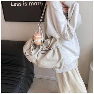 Detail of beige nylon drawstring crossbody bag with side pleats and coffee cup plush charm