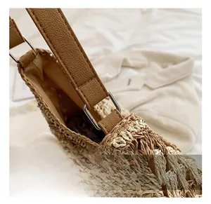 Detail of silver square metal buckle and brown pebbled leather strap on straw tote