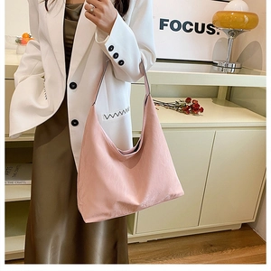 Détail du sac hobo en cuir PU rose clair porté avec une robe olive dans un décor cosy