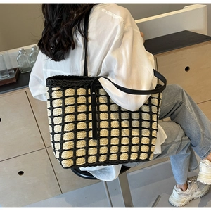 Détail du sac cabas en paille minimaliste avec motif de grille noire et cuir noir