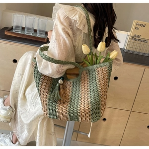 Detail of woven tote bag in green and wood tones with tassel pendant and flower inside