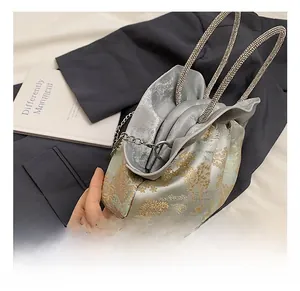 Detail of silver evening clutch featuring gold tree embroidery and rhinestone handles