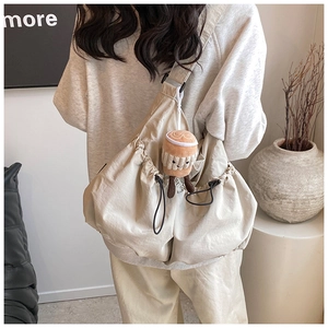 Close-up of beige crossbody bag with drawstring design and cute coffee plush charm