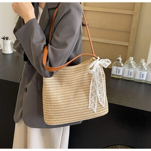 Détail du sac cabas en paille tissé à la main avec un grand nœud en dentelle blanche
