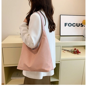 Détail d'un sac hobo rose pâle en nylon de qualité porté à l'épaule pour femme