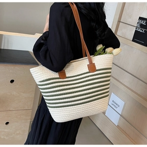 Detail of woven tote bag with green stripes and brown leather shoulder straps
