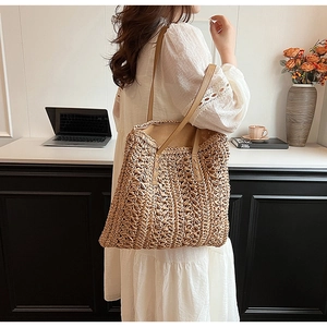 Detailed macro view of woven straw tote bag texture with khaki PU leather strap