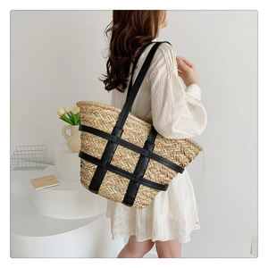 Detailed back view of a large woven straw tote bag with black leather grid and straps
