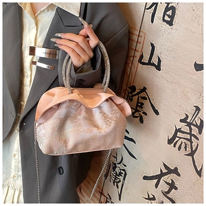 Close-up of pink jacquard satin handbag with rhinestone handles and chain strap