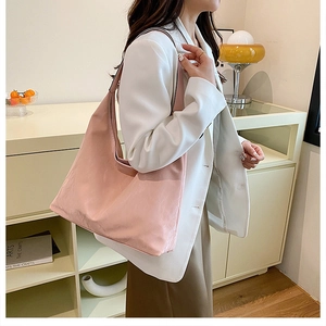 Gros plan d'un sac cabas en similicuir rose pâle avec texture douce et larges bretelles