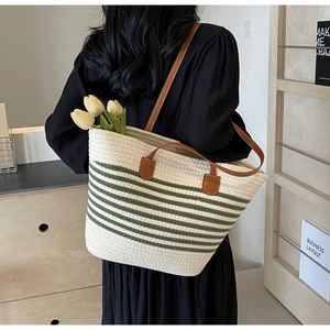 Detail of woven rope tote bag featuring green stripes and brown leather handles