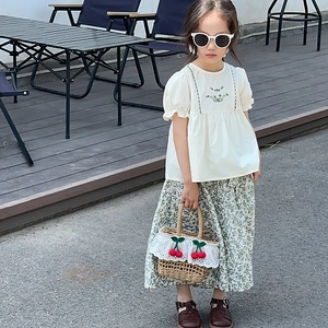 Close-up of girls' white cotton shirt with bubble sleeves and green floral embroidery