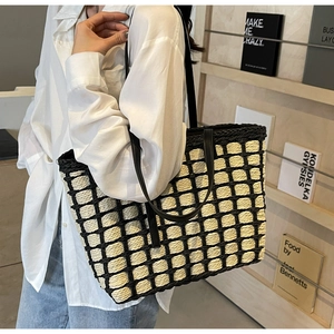 Détail du sac cabas tissé à carreaux avec anses en cuir noir porté par un mannequin de profil