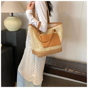 Detail view of woven straw tote bag with brown PU leather strap on shoulder