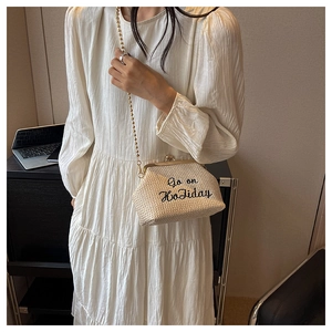 Détail du sac bandoulière beige tissé avec le slogan noir brodé Go on Holiday