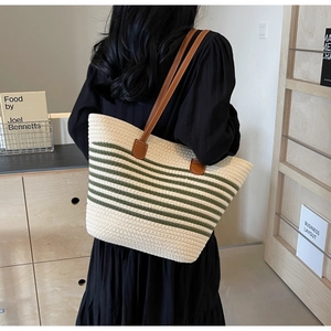 Close-up of woven tote bag with green stripes and brown leather shoulder straps