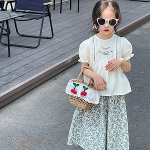 Detail of girls' summer set featuring floral skirt and white embroidered puff sleeve top