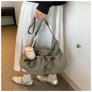 Olive green nylon crossbody bag detail with drawstring pockets and plush charm