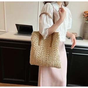 Detail of hand-woven straw tote bag with brown leather handle for summer vacation styling