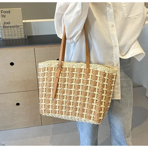 Gros plan d'un sac cabas en paille tressée avec des anses en cuir marron chic