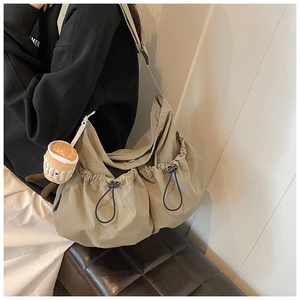 Detail of khaki nylon crossbody bag with double drawstring pockets and plush charm