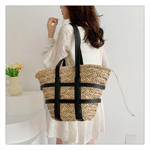 Detail of hand-woven straw tote bag with black leather frame and drawstring liner