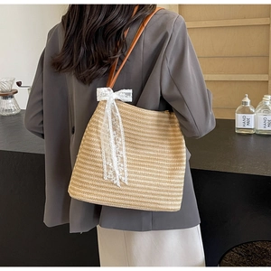 Détail d'un sac en paille tissé avec un nœud en dentelle blanche et bandoulière