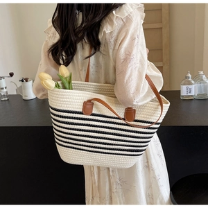 Detail of hand-woven beige rope tote with black stripes and brown leather straps