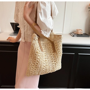 Minimalist cream straw tote bag with brown leather handles worn by a model in office setting