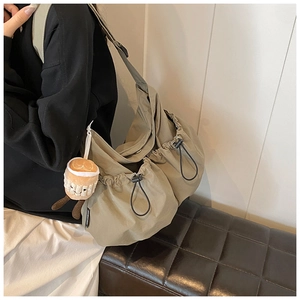 Close-up of casual nylon crossbody bag with drawstring design and cute plush charm