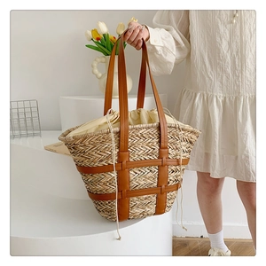 Detail of hand-woven straw tote bag with brown leather straps and drawstring liner