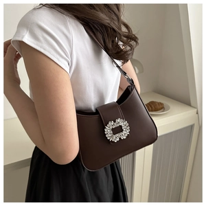 Detail of a dark brown PU leather underarm bag with a sparkling rhinestone buckle and strap