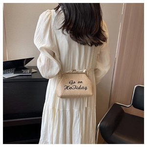Détail du sac bandoulière en paille beige avec broderie Go on Holiday et chaîne dorée