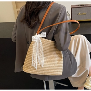 Détail du sac à bandoulière en paille tressée avec bandoulière cuir et nœud dentelle