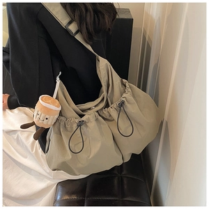 Detail of olive green nylon crossbody bag with drawstring side and cute plush charm
