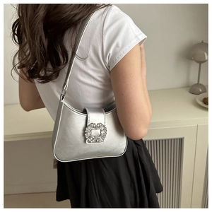 Silver PU leather underarm bag with a crystal buckle shown on model in a modern interior