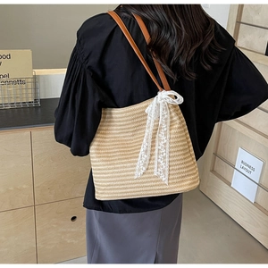 Vue détaillée d'un sac cabas en paille avec lanières en cuir marron et nœud en dentelle