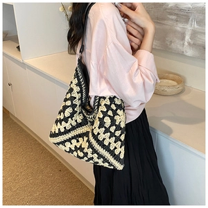 Close-up of black and white crochet straw tote bag with hollow flower weaving detail