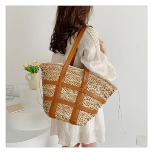 Detail of hand-woven straw tote with brown leather cage and drawstring inner pouch