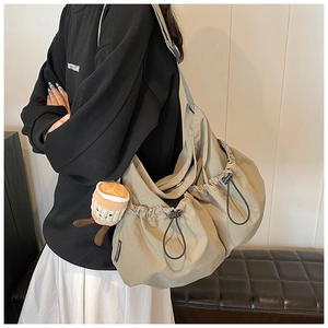 Detailed shot of spacious nylon crossbody bag with drawstring design and plush charm