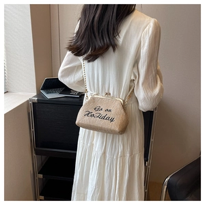 Détail du sac en paille tissé main avec broderie noire et bandoulière chaîne dorée