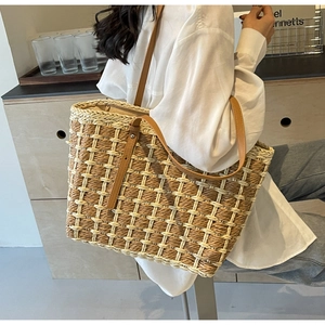 Détail du grand sac cabas en paille tissée avec anses en cuir brun et motif à carreaux