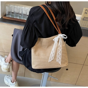 Sac fourre-tout en paille avec lanières brunes et nœud en dentelle blanche sur modèle