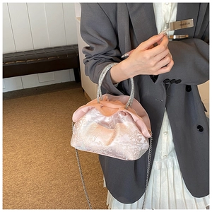 Detail of pink jacquard satin handbag featuring a crystal-embellished handle and silver chain