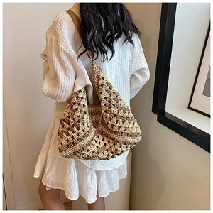 Detailed view of large straw tote bag featuring contrast leather straps and woven texture