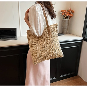 Detail of hand-woven straw tote with brown leather handles in a chic office setting