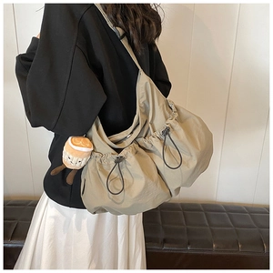 Detail of khaki nylon crossbody bag with drawstring pockets and a cute plush charm