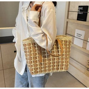 Détail d'un sac cabas en paille tressée avec lanières en cuir et motif à damier