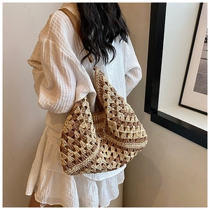 Detail of hand-woven straw tote bag with geometric pattern and brown leather strap